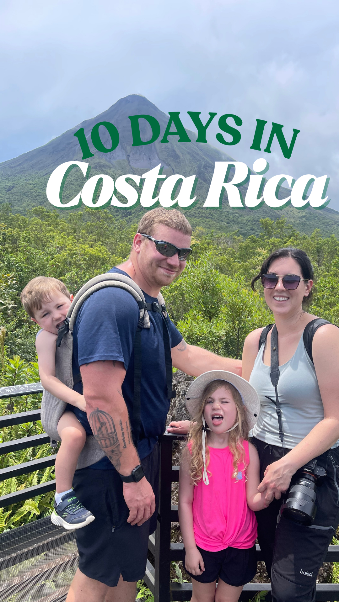 Family of 2 adults and 2 children posing and smiling in front of Arenal volcano in Costa Rica