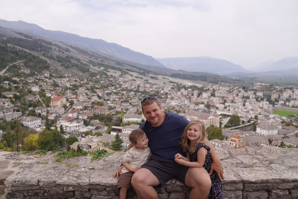 a father and 2 kids smiling and posing for a photo at a viewpoint in Gjirokaster albania