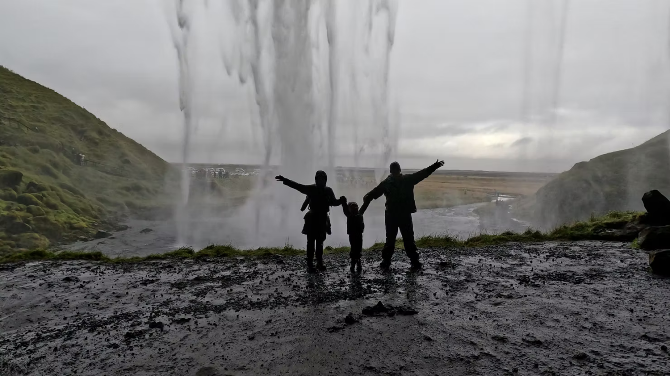 silhouette of family standing behind seljalandsfoss waterfall in Iceland