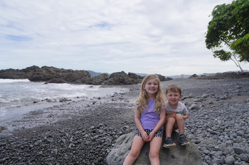 2 young kids sitting on a rock on a beach in Costa Rica